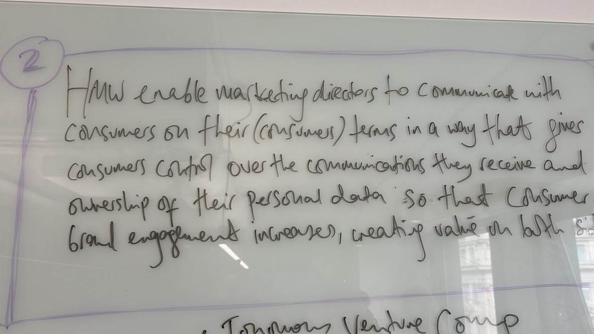 Whiteboard from a NEOM venture studio workshop with a hand-written 'How might we' problem statement.